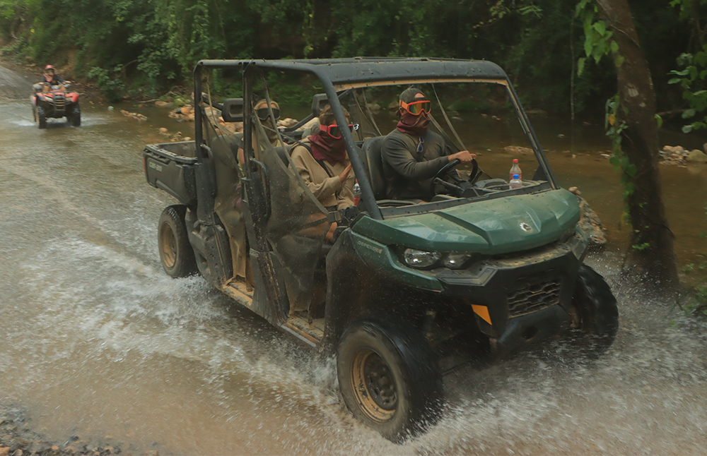 RZR todo terreno cruzando un río en un paisaje natural, mostrando su resistencia y capacidad de manejo en terrenos difíciles.