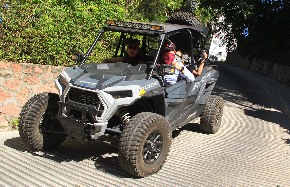 Grupo de personas junto a un vehículo RZR todo terreno, listos para una aventura al aire libre en un paisaje natural