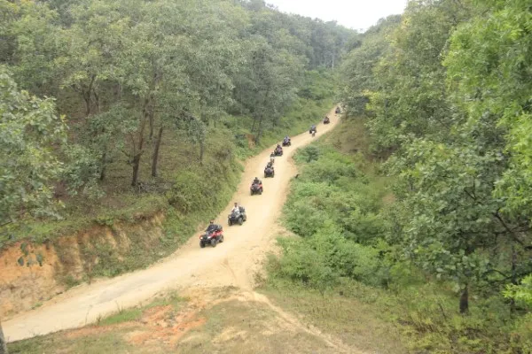 A line of rzr vehicles drives along a lush hillside trail as part of a guided atv tour in Puerto Vallarta with panoramic views