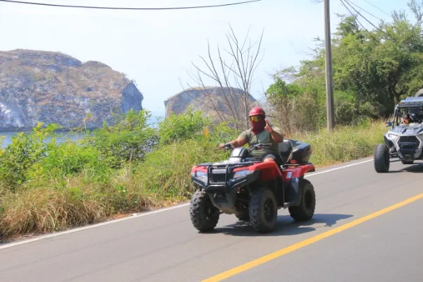 A person rides through a lush mountain trail on an all-terrain vehicle, fully enjoying an adventure tour in the wilderness with a rzr/utv experience