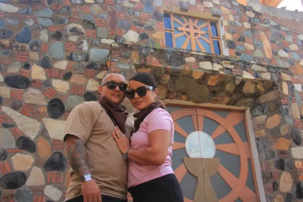 A couple stands happily in front of a traditional church in a small town visited during their cultural atv tour in Puerto Vallarta