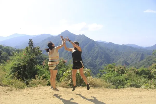 Two young women raise their arms and cheer after reaching a breathtaking mountain viewpoint on an exciting atv tour in Puerto Vallarta