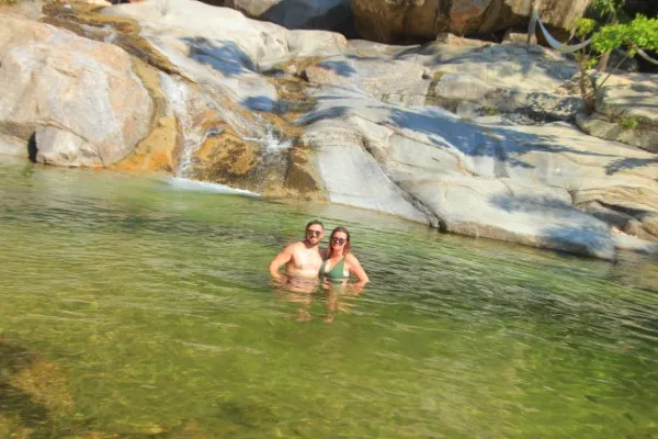 A couple soaks in warm, natural spring water surrounded by trees, embracing a peaceful and rejuvenating moment at the hot springs attractions
