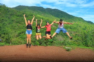 A group of people taking part in one of the family tours jumps joyfully in front of a mountainous landscape, celebrating a moment full of energy and nature.