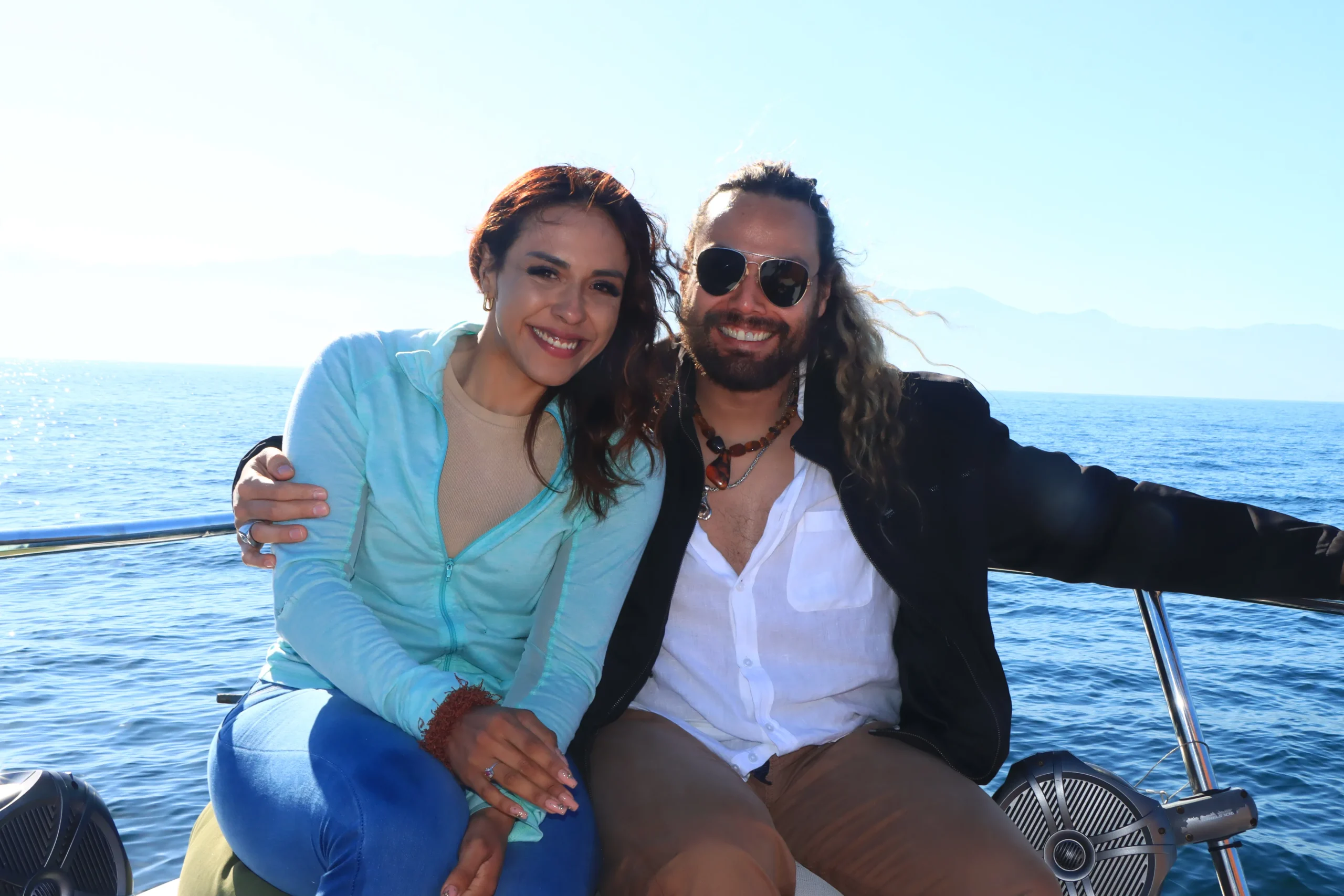 Whale watching experience with two people sitting closely on a boat surrounded by calm sea.