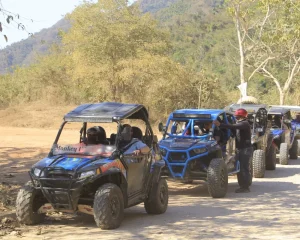 RZR vehicles line up along an all terrain road, ready to explore the rugged landscape.