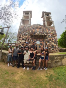A group of visitors poses in front of a stone structure with towers as part of their Hot springs tour experience.