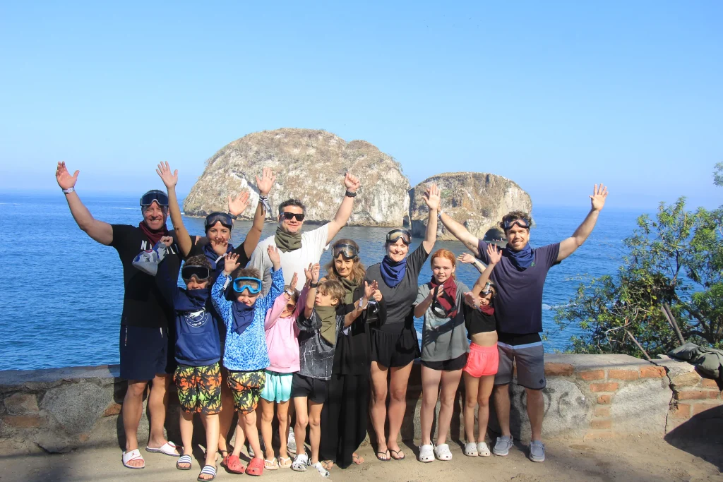 A group of travelers smiles in front of the sea and rock formations, sharing the excitement of an Extreme adventure Puerto Vallarta.