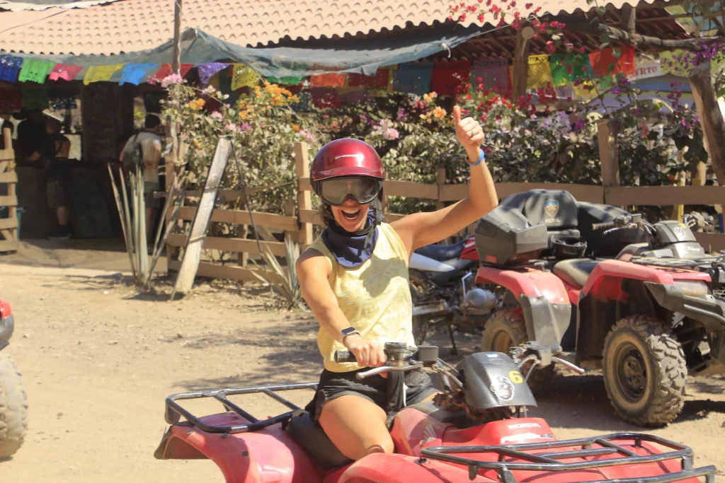A participant rides an ATV and waves with excitement during a day of Extreme adventure Puerto Vallarta. 