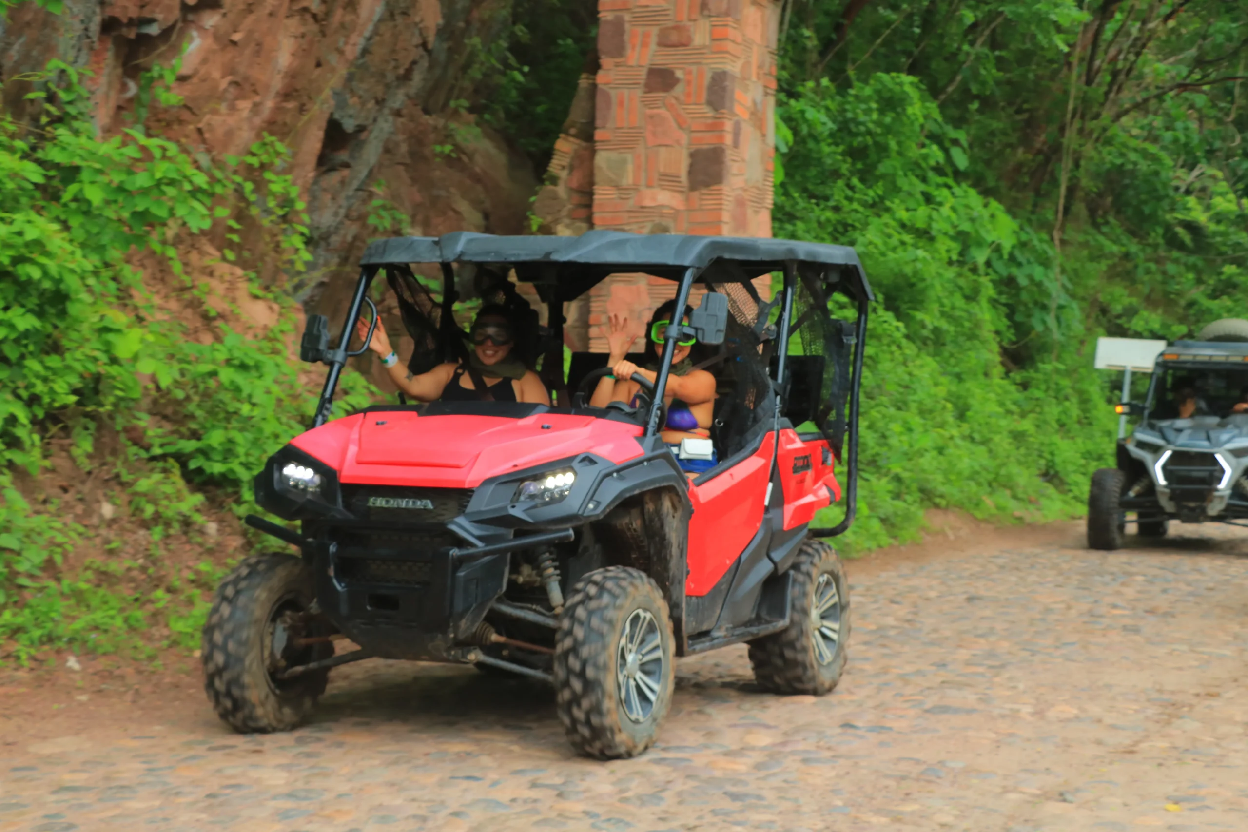 A red RZR moves along a path surrounded by nature, reflecting the jungle contact experienced in Puerto Vallarta RZR Tours.