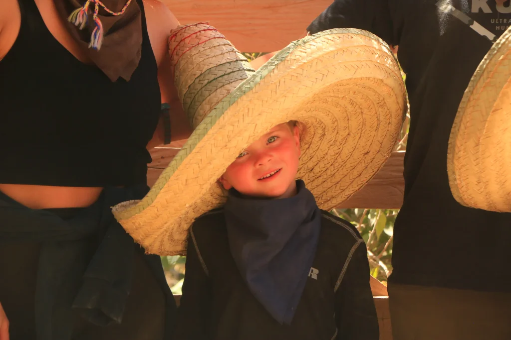 A smiling boy hides under a giant sombrero, showing a cultural side of the things to do in Puerto Vallarta with kids.