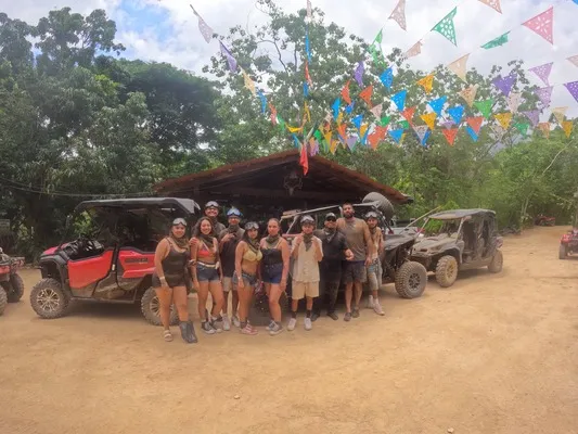A group of travelers gathers before starting their route, surrounded by colorful flags and ready for a day of ATV and RZR Adventures.
