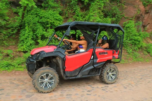 Two people drive a red RZR through a forest trail, capturing the essence of ATV and RZR Adventures in motion.