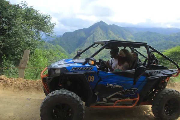 A RZR drives along a mountain trail surrounded by nature and panoramic views of the highlands.
