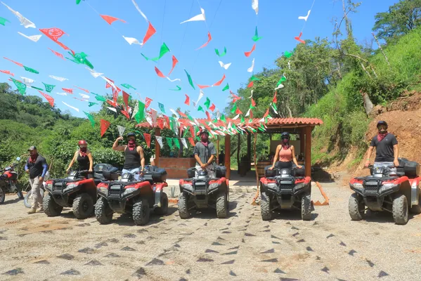 Several UTVs and ATVs are parked under colorful flags, ready to explore the rural trails surrounded by nature.