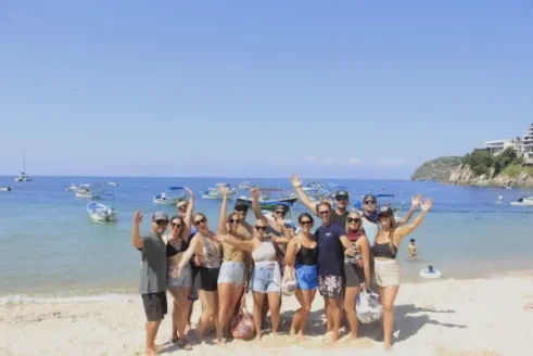 A Group Of People Poses By The Sea While Several Boats Float In The Background, Creating A Perfect Setting To Begin A Boat Ride Along The Coast.