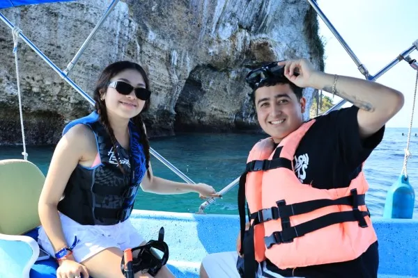 A couple wearing life jackets pauses near rock formations during a Boat ride, taking a moment to appreciate the scenery.