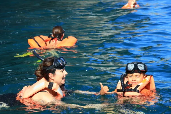 Jungle boat ride with Mom swimming alongside her son, a safe, joyful, and fun-filled water activity.